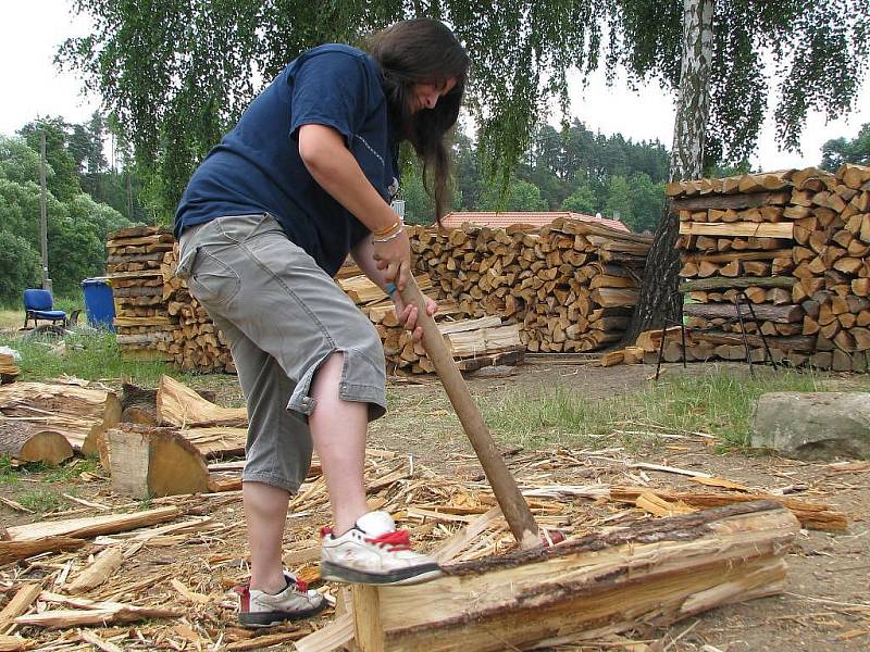 Jednou z mnoha činností v Podcestném mlýně je zpracování dřeva. Výtěžek z něj putuje zpět na podporu komunity. S obrovskými špalky zápasí i Katka.