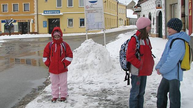 Dokunžacké školy dojíždí řada dětí z okolních vesnic, na snímku čekají na autobusové zastávce na náměstí v Kunžaku. 