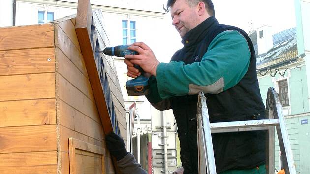 Pracovníci služeb města Jan Mach a František Hornyk (v pozadí) demontují stánek na jindřichohradeckém náměstí Míru.