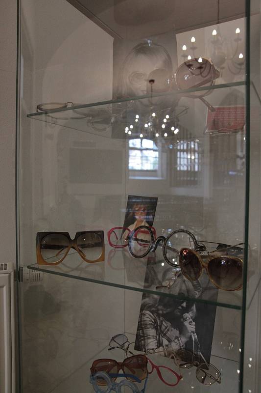 Brýle ve vitríně doplňují fotografie Nadi Urbánkové.