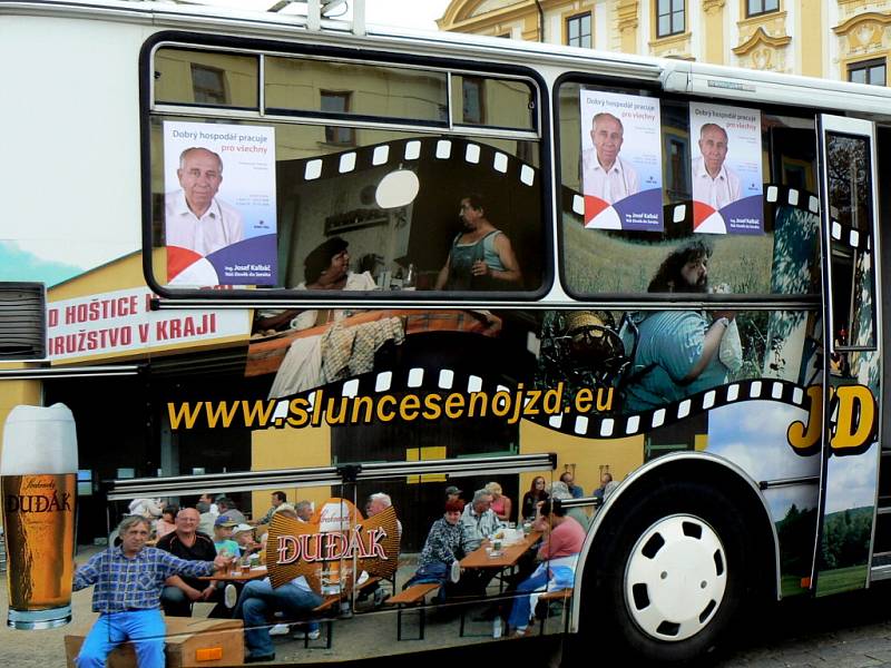 JZD Hoštice u Volyně podpořilo kandidáta lidovců Josefa Kalbáče do senátu. Autobus JZD Hoštice u Volyně je vyzdoben snímky z Troškovy trilogie Slunce, seno ... a záběry z obce Hoštice. 