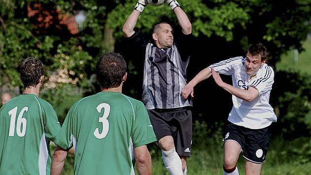 Domácí brankář Roman Jelínek chytá ve výskoku míč před dotírajícím Davidem Pichlíkem v utkání minulého kola krajského fotbalového přeboru, ve kterém Čížová hrála s Pískem B 0:0. 