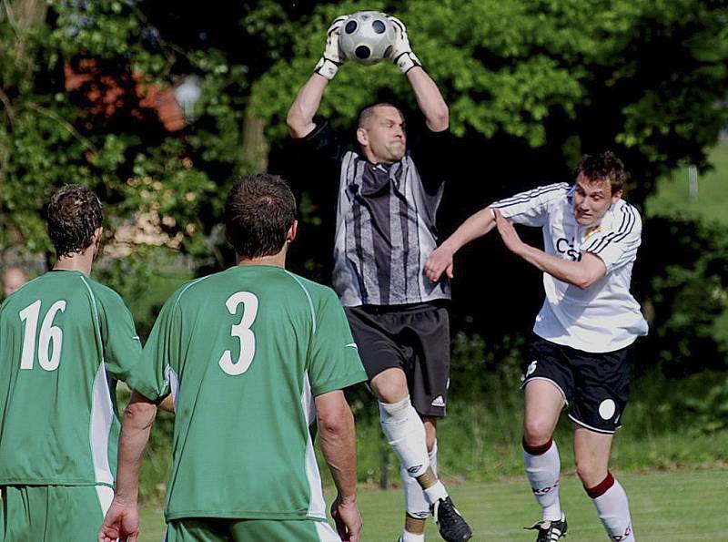 Domácí brankář Roman Jelínek chytá ve výskoku míč před dotírajícím Davidem Pichlíkem v utkání minulého kola krajského fotbalového přeboru, ve kterém Čížová hrála s Pískem B 0:0. 