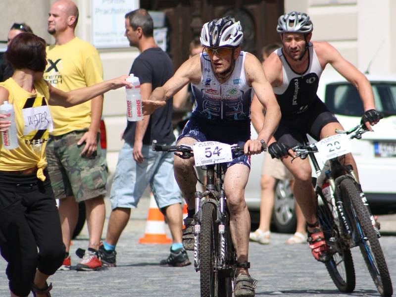 Hlavní závod se dostal na Velké náměstí v Prachaticích. Závodníci vjíždějí do druhého kola cyklistické části hlavního závodu.