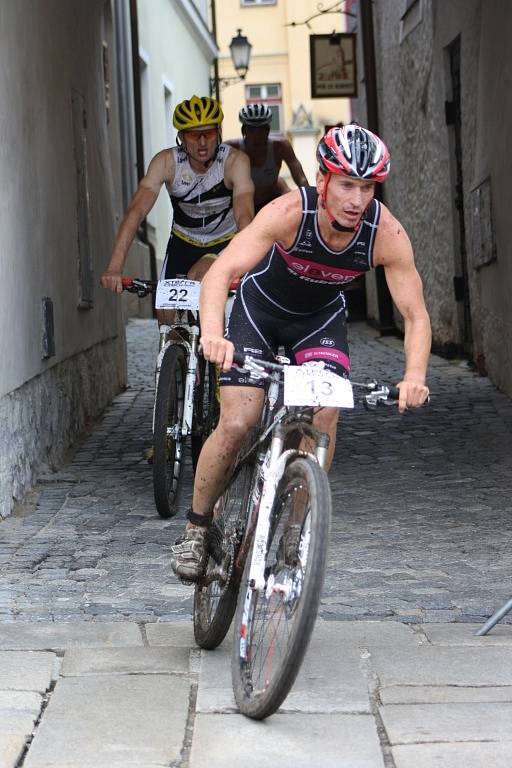 Hlavní závod se dostal na Velké náměstí v Prachaticích. Závodníci vjíždějí do druhého kola cyklistické části hlavního závodu.