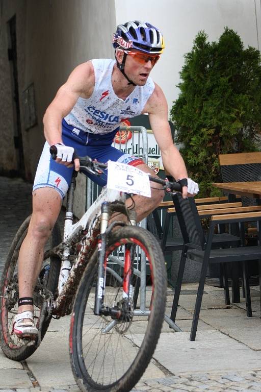 Hlavní závod se dostal na Velké náměstí v Prachaticích. Závodníci vjíždějí do druhého kola cyklistické části hlavního závodu.