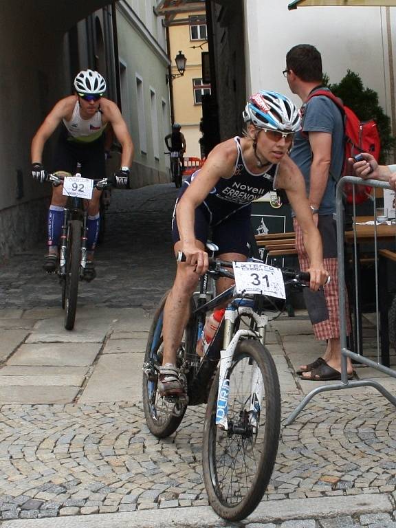 Hlavní závod se dostal na Velké náměstí v Prachaticích. Závodníci vjíždějí do druhého kola cyklistické části hlavního závodu.