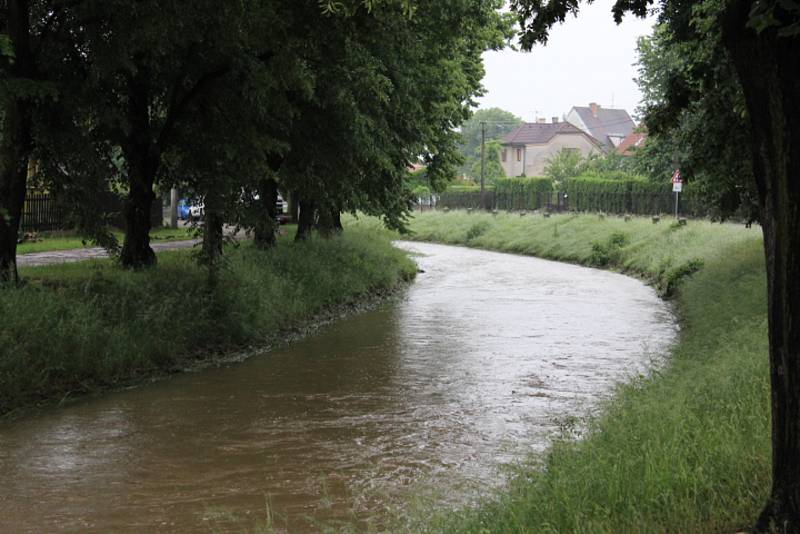 Rozbouřený Stroupínský potok zablokoval ve Hředlích komunikaci směrem na Točník.