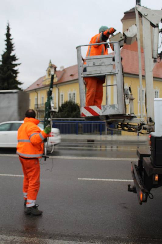 Zaměstnanci technických služeb uklízejí svítící sněhové vločky z ulic města. Další den je čekají ještě stromy.