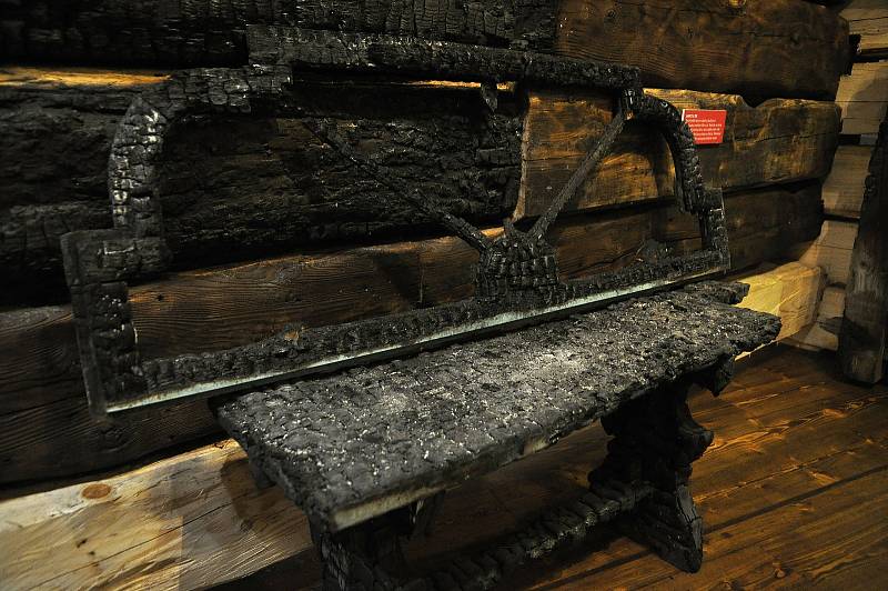 Zuhelnatělá lavice z jídelny Libušín vystavená v Sušáku ve Valašském muzeu v přírodě. Dochovala se proto, že stála u zdi. Byla tak na okraji požářiště, kde byl žár o něco slabší; Valašské muzeum v přírodě v Rožnově, Sušák, 1. patro, srpen 2020