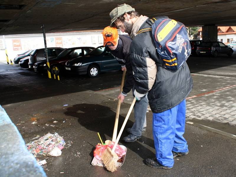 Pracovníci veřejné služby a veřejně prospěšných prací uklízejí odpadky, které se objevily po roztátí sněhu.