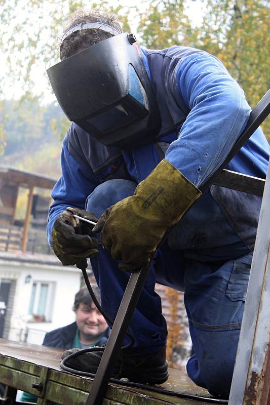 Řemeslníci Antonín Hajda (ve vestě) a Radek Machala (v modrém) z Ratiboře opravují v Oznici odchytovou klec na toulavého medvěda. Asistuje také starosta obce Oznice Martin Gerža (vlevo). Klec byla přivezena ze Slovenska z oblasti Malé Fatry.