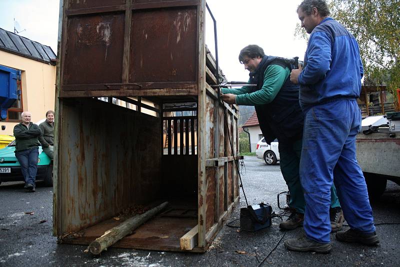 Řemeslníci Antonín Hajda (ve vestě) a Radek Machala (v modrém) z Ratiboře opravují v Oznici odchytovou klec na toulavého medvěda. Asistuje také starosta obce Oznice Martin Gerža (vlevo). Klec byla přivezena ze Slovenska z oblasti Malé Fatry.