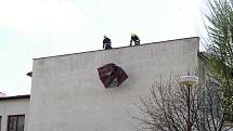 Hasiči zabezpečují střešní krytinu, kterou strhl silný vítr ze střechy Masarykova gymnázia ve Vsetíně ve středu 24. dubna 2019.