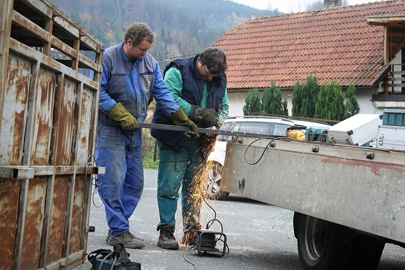 Řemeslníci Antonín Hajda (ve vestě) a Radek Machala (v modrém) z Ratiboře opravují v Oznici odchytovou klec na toulavého medvěda. Asistuje také starosta obce Oznice Martin Gerža (vlevo). Klec byla přivezena ze Slovenska z oblasti Malé Fatry.