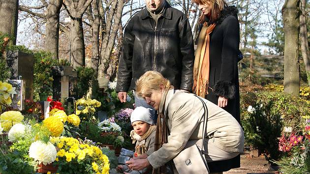 Dušičky jsou tady. Na hroby chodí položit květiny a věnce celé rodiny. Tato přišla dopoledne, ale pro někoho je lepší noc.