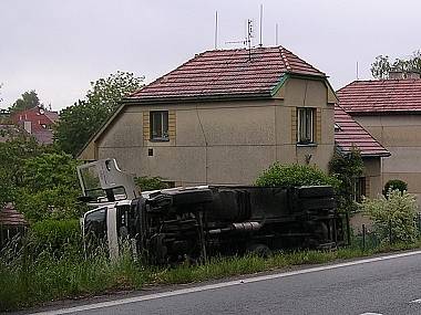 Kamion zůstal ležet na boku mimo silnici.