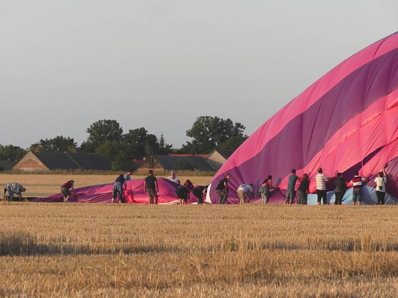Účastníci zážitkového letu pomáhají po přistání při balení balónu.