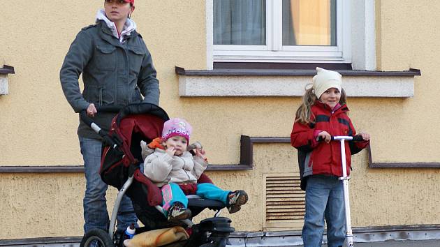 Rodinka na kolečkách: miminko v kočárku, dcerka na koloběžce a maminka dokonce na kolečkových bruslích vyrazili na jarní procházku.