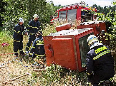 Hasiči vyprošťují převrácený traktor.