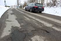 Silnice ve Větrném Jeníkově je plná děr, opravy se dočká již letos.