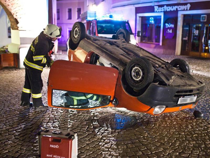 Nehoda na novoměstském náměstí, kde automobil narazil do pilíře domu v úzké části silnice a převrátil se na střechu.