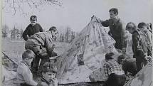 Branné cvičení žáků ZDŠ v Broumově. Na snímku je skupina dětí okolo dvou vojáků, kteří staví stan z celty.