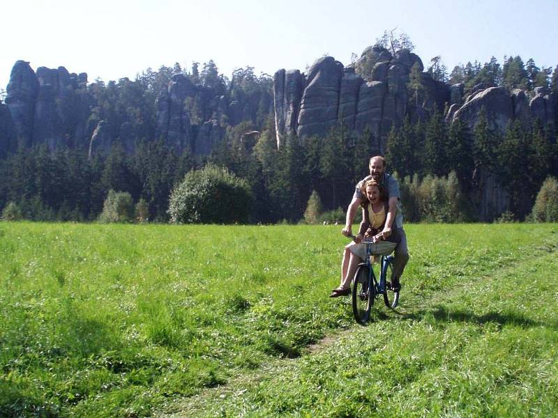 Hlavní  protagonisté filmu Eva Holubová a Jaromír Dulava na kole s pozadím skal.