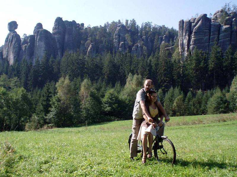 Hlavní  protagonisté filmu Eva Holubová a Jaromír Dulava na kole s pozadím skal. 