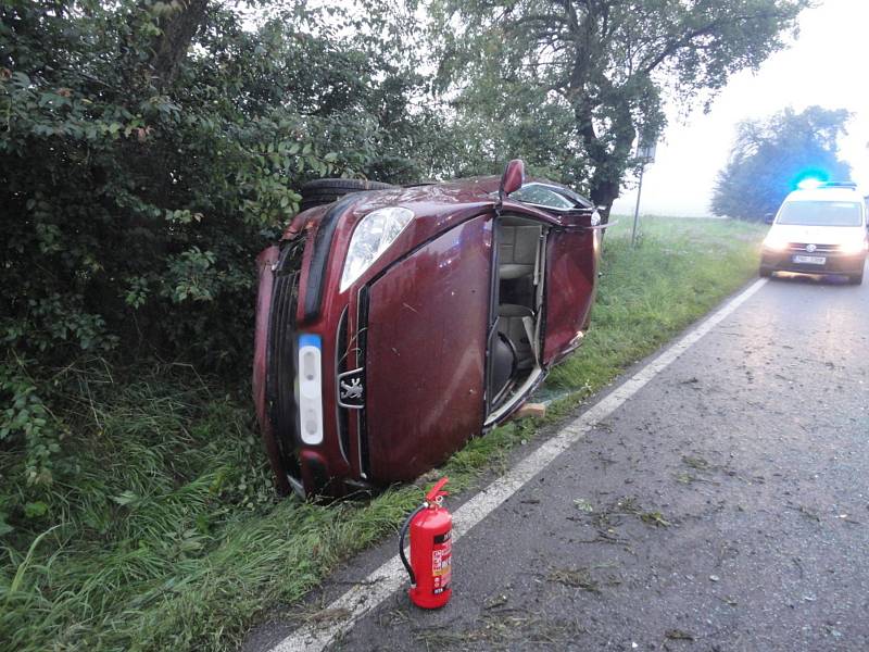 Automobil se převrátil při nehodě přes střechu a zůstal ležet na boku mimo komunikaci. Zpět na kola ho dostali hasiči.