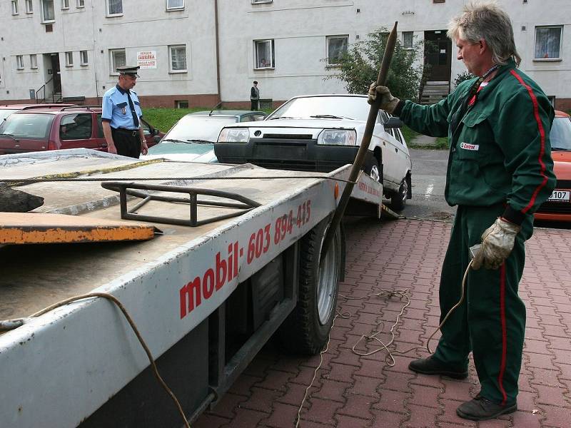 STRÁŽNÍCI městské policie za asistence odtahové služby odstraňují z komunikace automobil, který bránil provozu. 