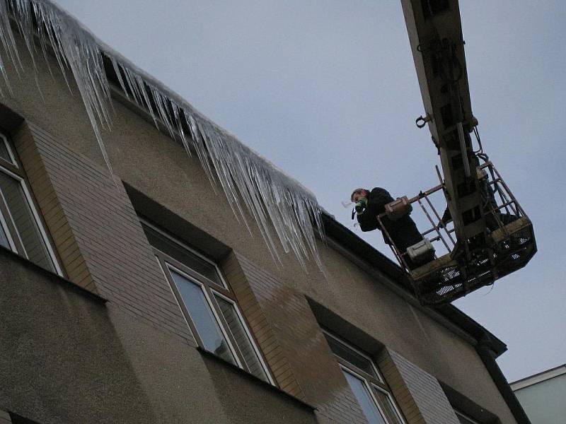 Pracovníci soukromé firmy strhávají největší rampouchy z budovy rychnovského Městského úřadu.