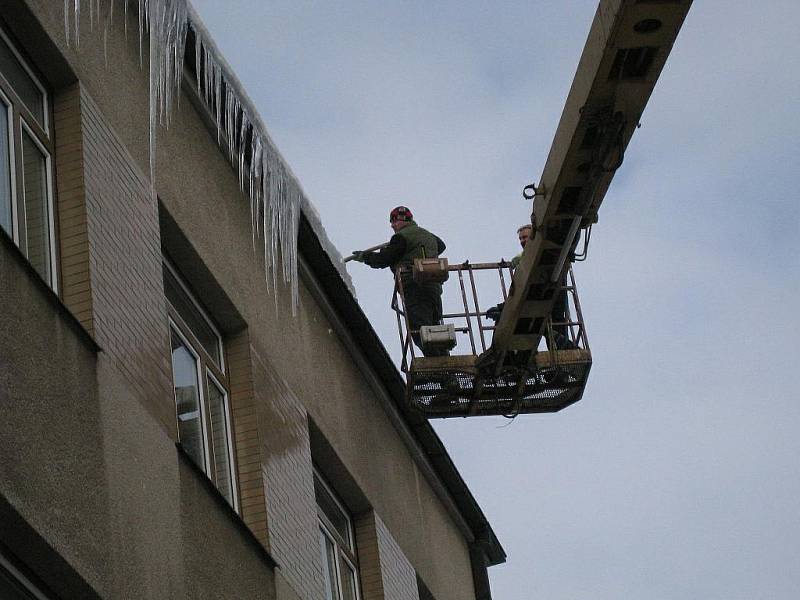 Pracovníci soukromé firmy strhávají největší rampouchy z budovy rychnovského Městského úřadu.