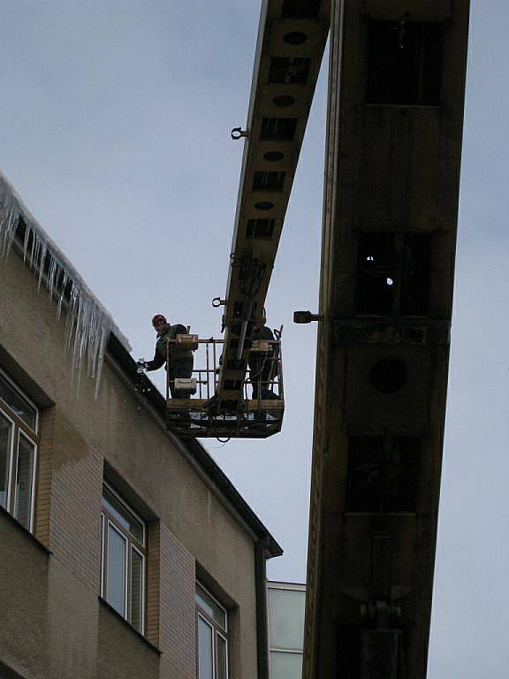 Pracovníci soukromé firmy strhávají největší rampouchy z budovy rychnovského Městského úřadu.