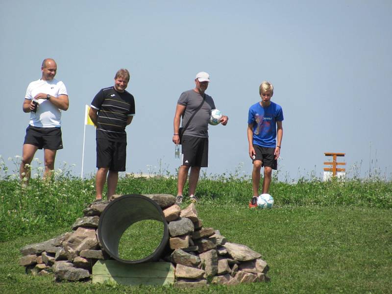 PŘES PŘEKÁŽKY DO JAMKY. Cílem hráče ve fotbalgolfu je stejně jako v golfu jamka (na snímku vlevo). Do ní se snaží trefit fotbalový míč. Po cestě zdolává překážky v podobě kamenů, dřevěných překážek a podobně.