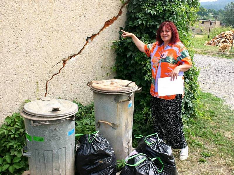 Obyvatelka jednoho z bytových domů Libuše Kozáková ukazuje na praskliny, které způsobila voda tekoucí po rozbité silnici přímo pod dům.