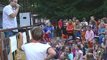 Michal Hudček zpívá sto šedesáti dětem na improvizovaném pódiu tábora Balda