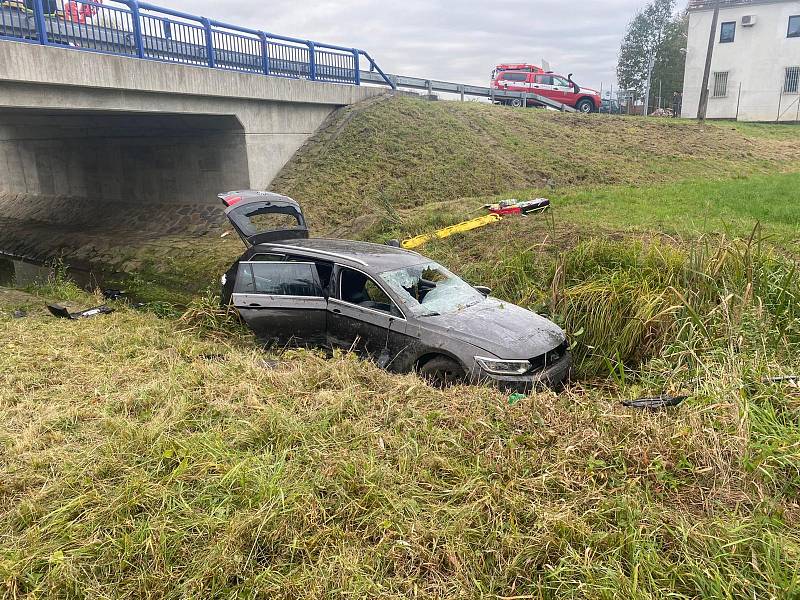 Havarované vozidlo uvízlé v bahnitém potůčku zhruba tři metry pod vozovkou u Sukorad.