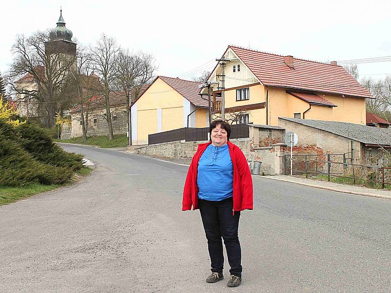 JANA SVOBODOVÁ, starostka Skalska, uprostřed obce. Nad ní se ukazuje historický kostel se zvonicí.