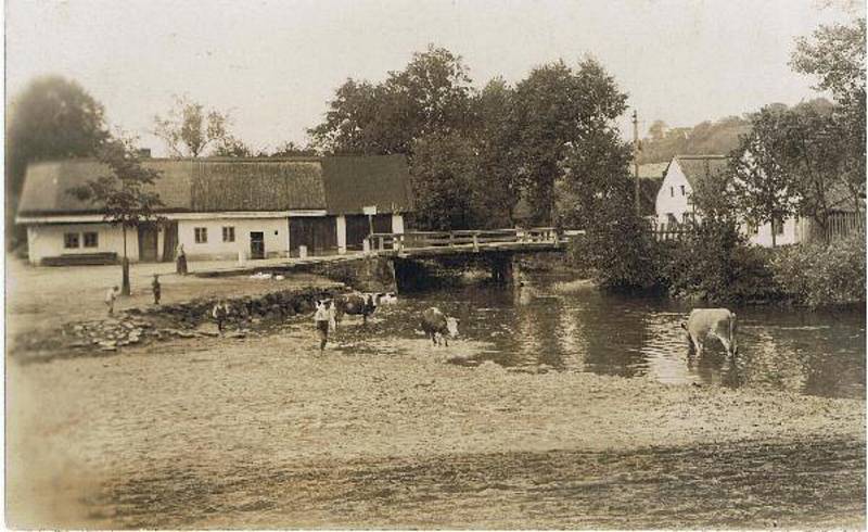 Náves s řekou Mohelkou a původním dřevěným mostem v roce 1918.