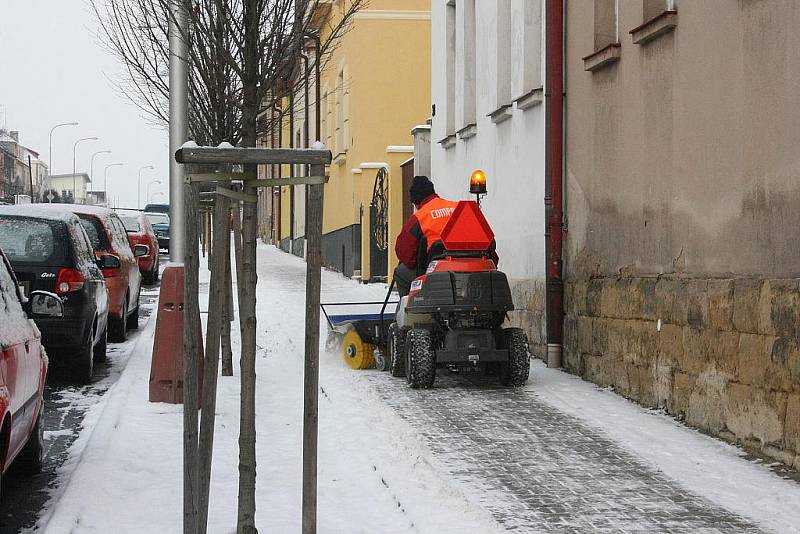 Malotraktor s kartáčem brázdí po chodnících města.