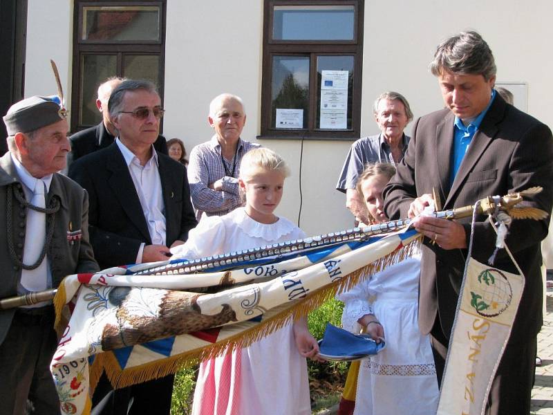 Starosta moravskobudějovického orla Petr Žák připevňuje štítek Jana Buly na ústřední orelský prapor Svatováclavské župy v exilu hned pod štítkem biskupa Berana.