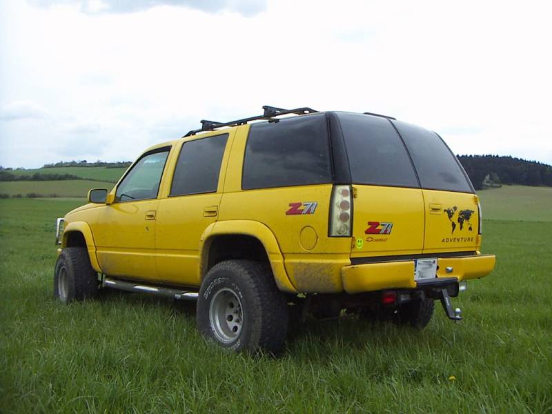Jasně žlutý Chevrolet Tahoe Z71 ročníku 1999 s pohonem všech čtyř kol. Na první pohled zaujme leštěná mřížka chladiče se symboly plamenů.