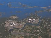 Lokalita (v popředí) s úložištěm ve Švédském Forsmarku. Je umístěno na mořském podřeží. V zadu je jaderná elektrárna s chlazením do moře. Zdejší důl je hluboký pouze 50 metrů.