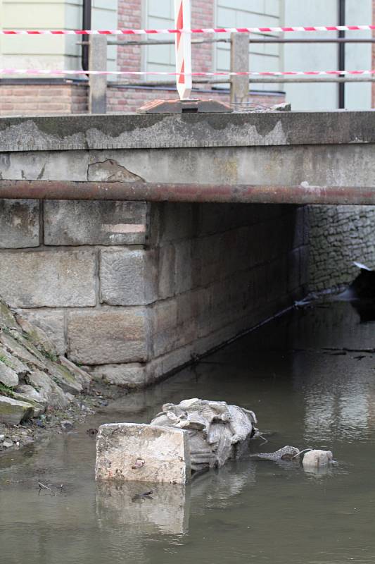 Barokní socha svatého Jana Nepomuckého sražená do koryta Stařečského potoka.