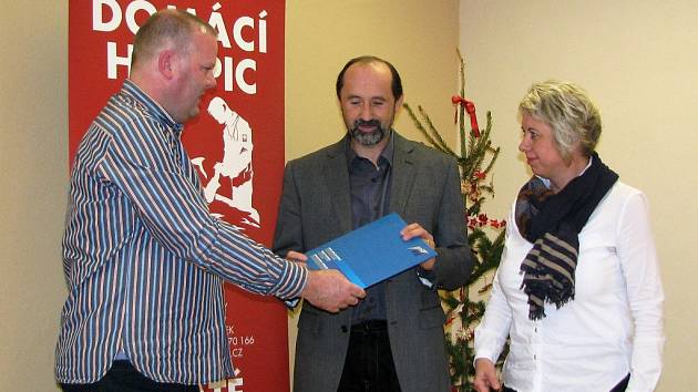 Ředitel firmy OSC předává řediteli charity Petru Jaškovi a vedoucí hospice Evě Vráblové smlouvu o daru.
