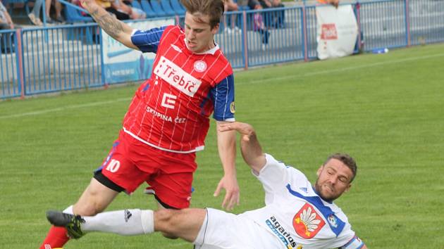 Třebíčský záložník Petr Ošmera (v červeném) se ve včerejším utkání snaží uniknout skluzujícímu kapitánovi Velkého Meziříčí Jaroslavu Krejčímu. 