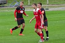Branka Vojtěcha Němce po rohovém kopu rozhodla o sobotní výhře 1:0 fotbalistů Okříšek (v červeném) na půdě Bystřice nad Pernštejnem (v černém).