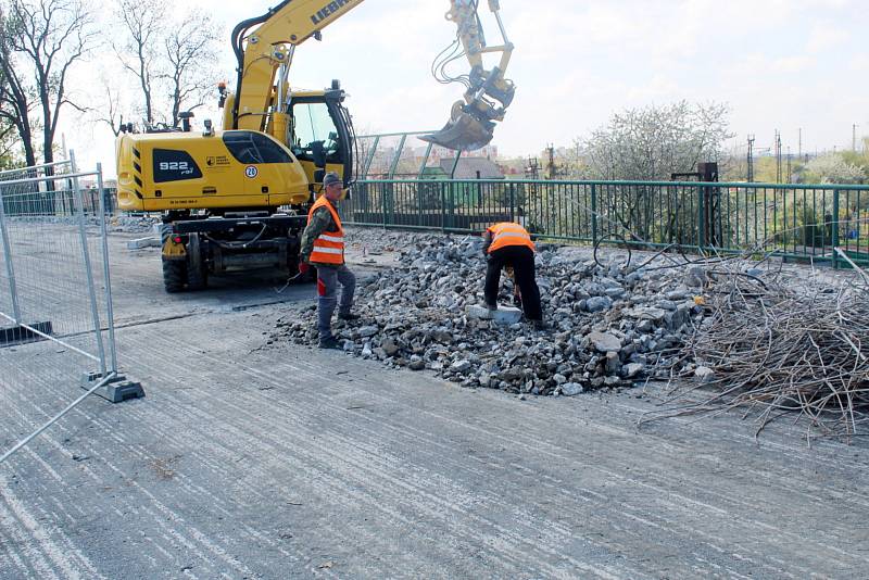 Na uzavřeném železničním nadjezdu v Nymburce dělníci s pomocí těžké techniky pracují na odstranění stávajících chodníků.