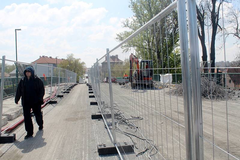 Na uzavřeném železničním nadjezdu v Nymburce dělníci s pomocí těžké techniky pracují na odstranění stávajících chodníků.